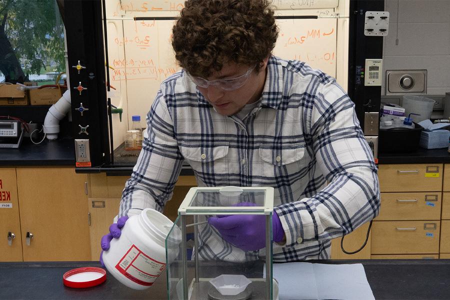 A student works in a lab while wearing safety glasses.